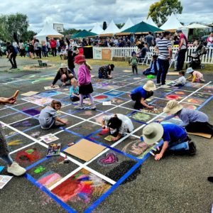 Stacey Bennett leading community chalk art mural at Winter Harvest Festival