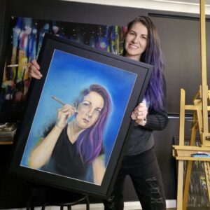 Stacey Bennett holding her pastel self-portrait