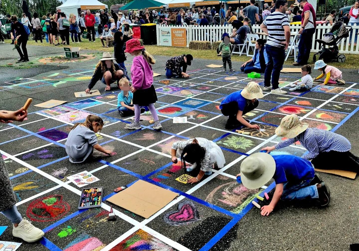 Stacey Bennett leading community chalk art mural at Winter Harvest Festival